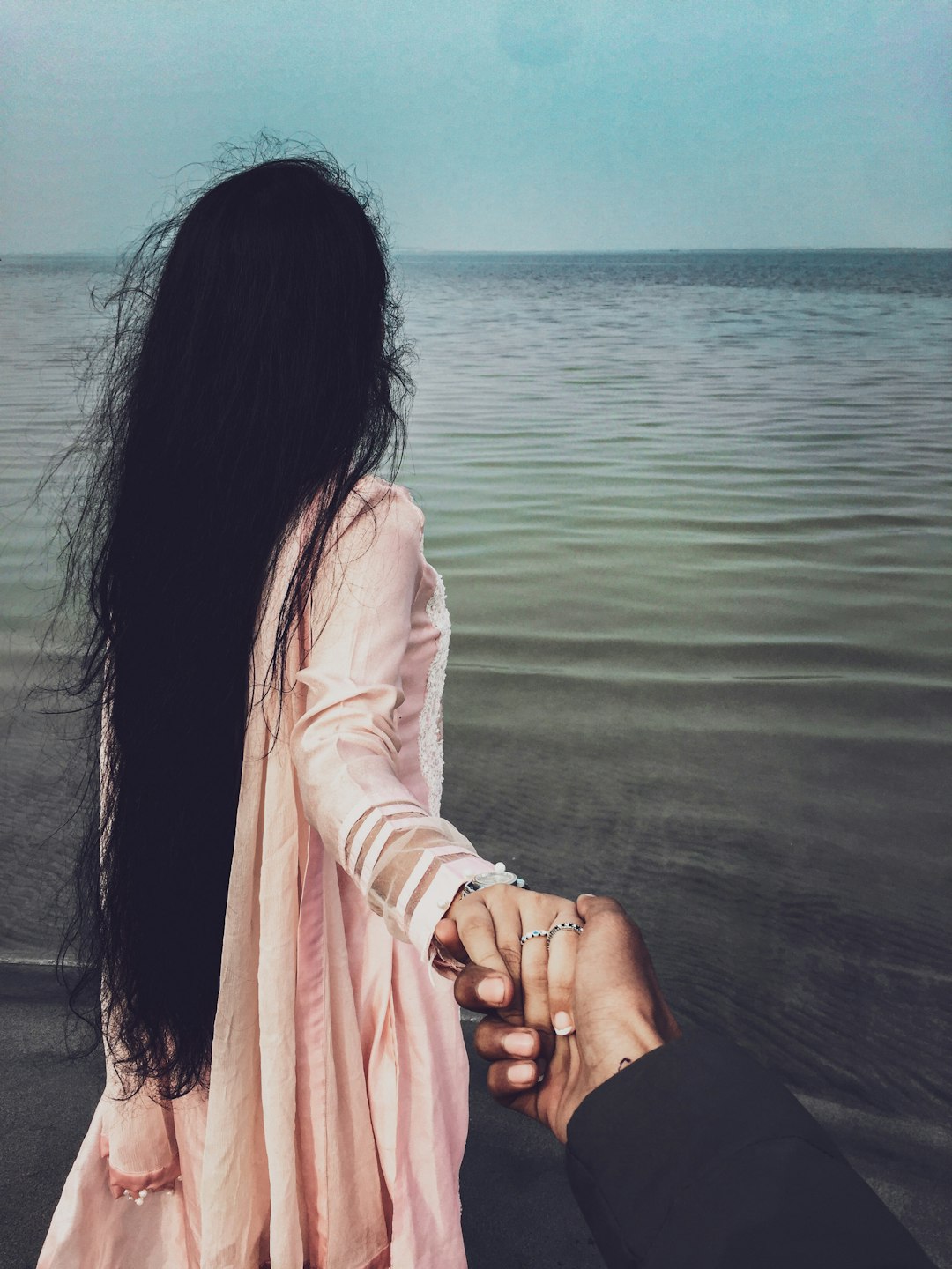 woman in white long sleeve shirt sitting on brown wooden dock during daytime