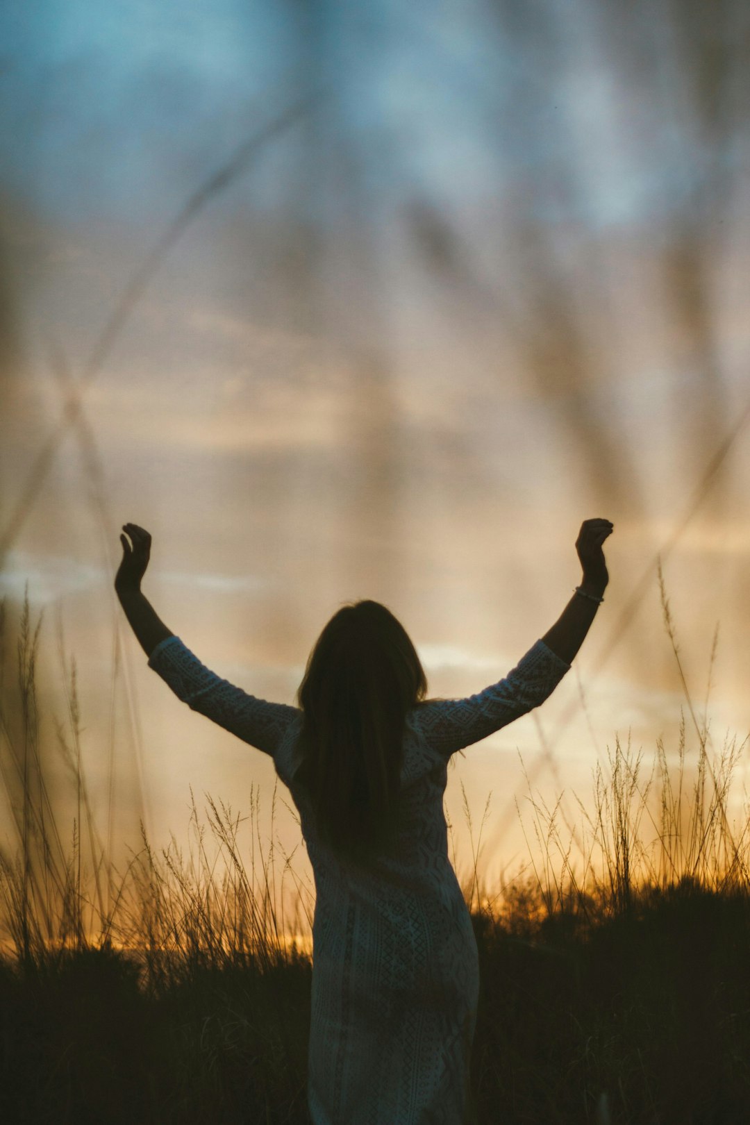 A woman standing in a field with her arms raised