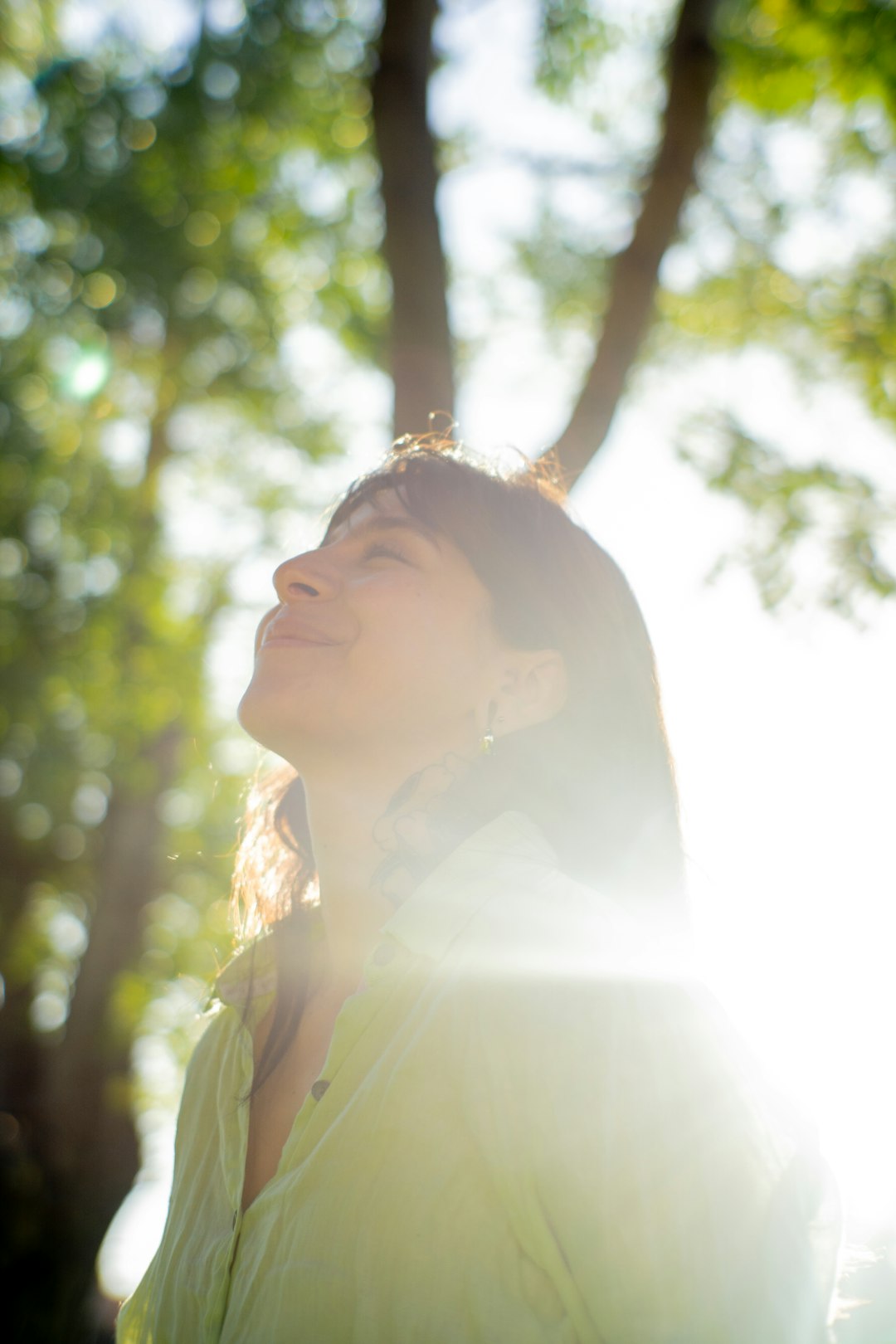 a woman standing in front of a tree with her eyes closed