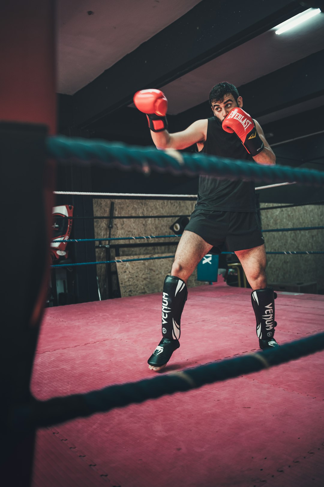 a man standing in a boxing ring holding a red boxing glove