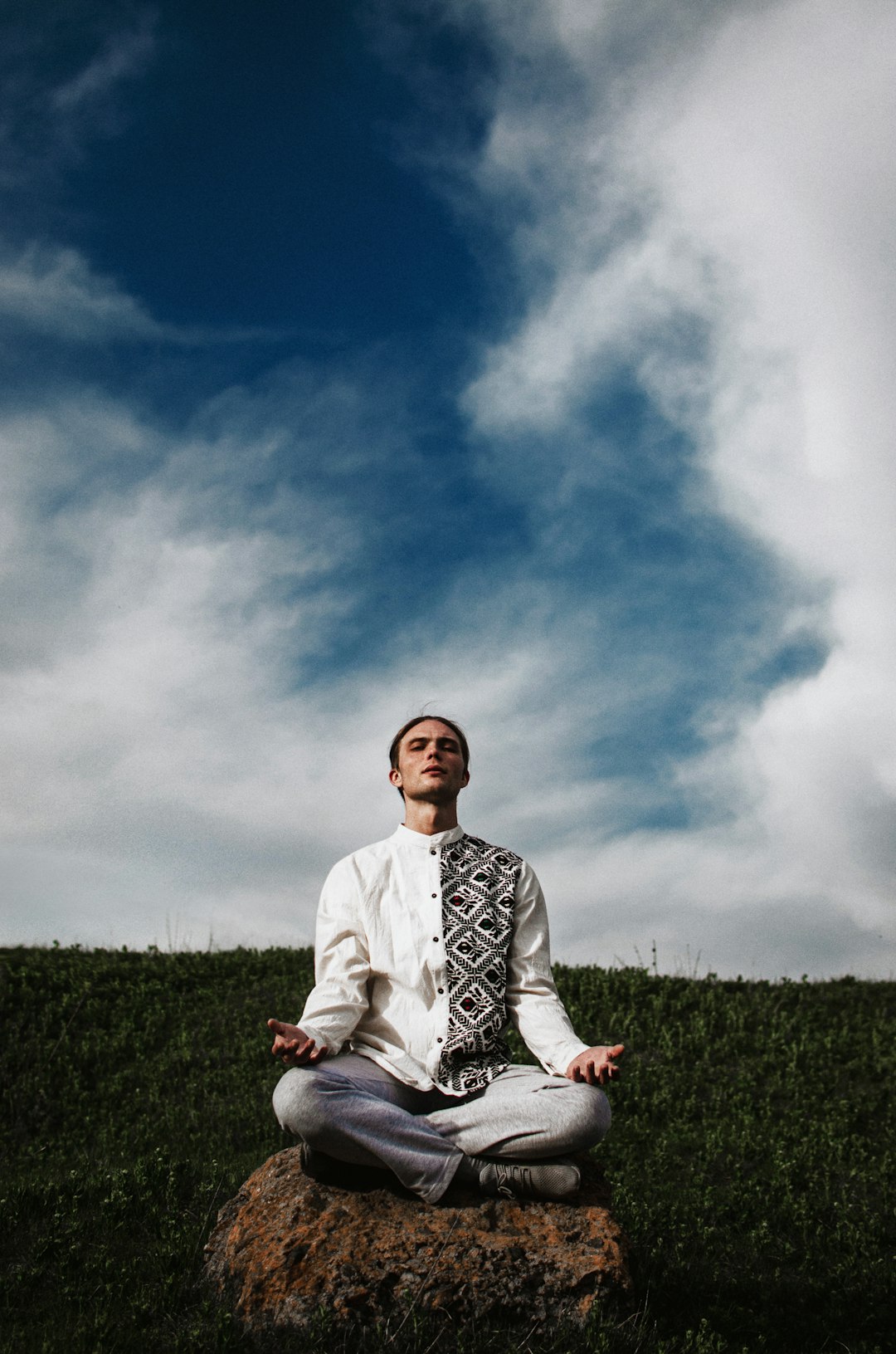 a man sitting on top of a rock in a field