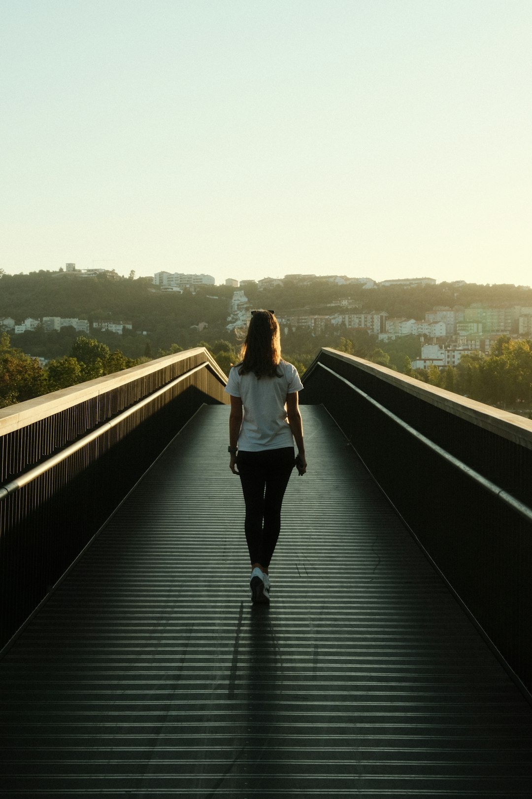 A woman walking across a bridge in the sun