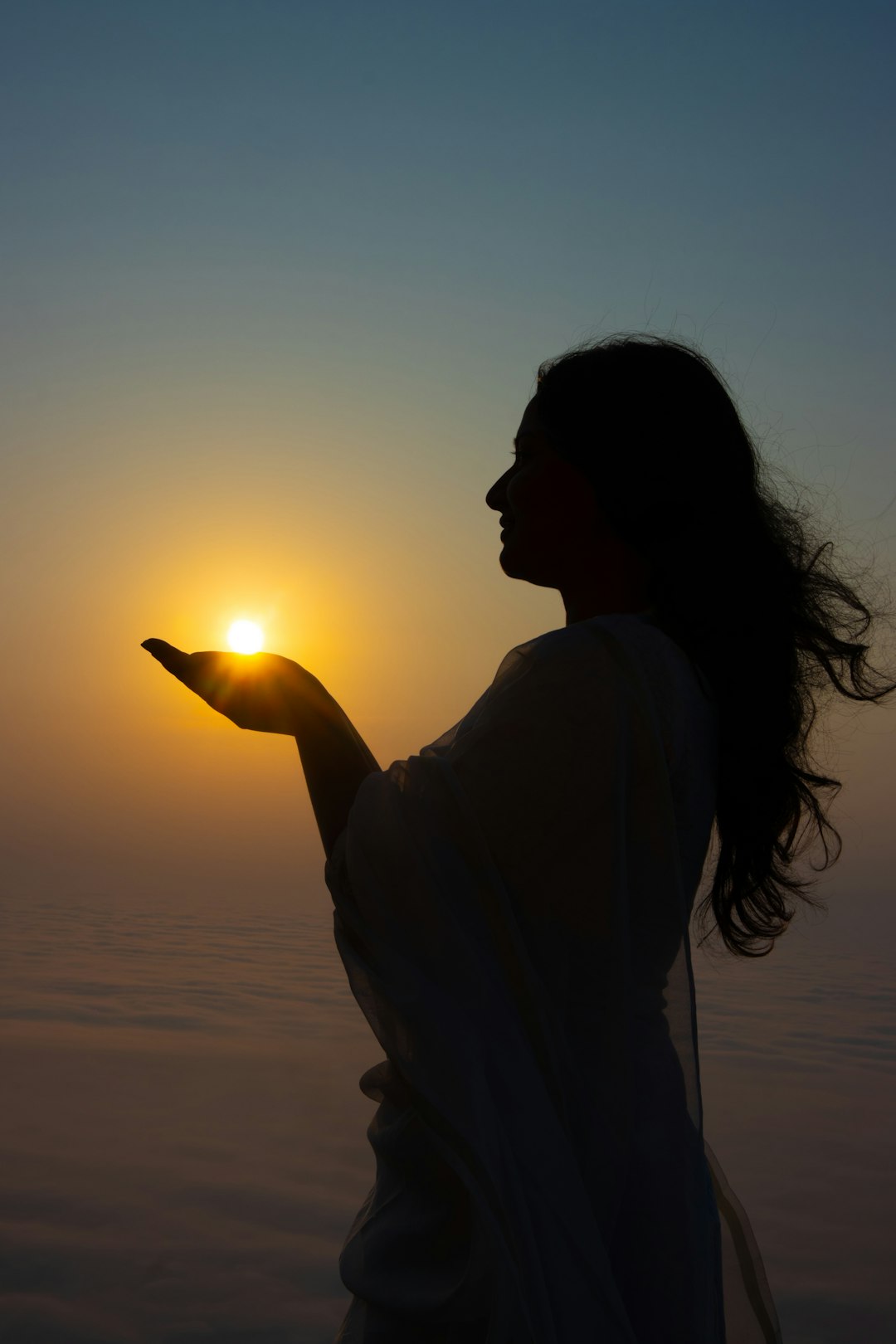 Woman holds the sun in her outstretched hand.