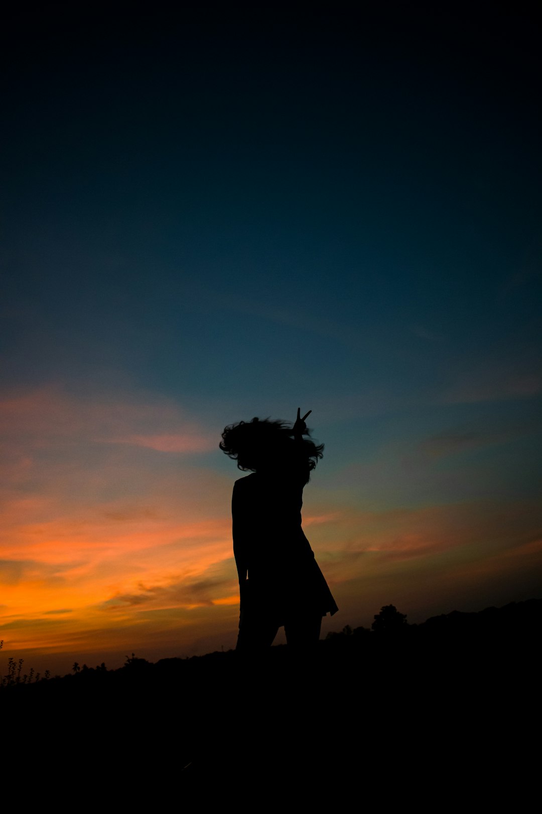 silhouette of woman standing on hill during sunset