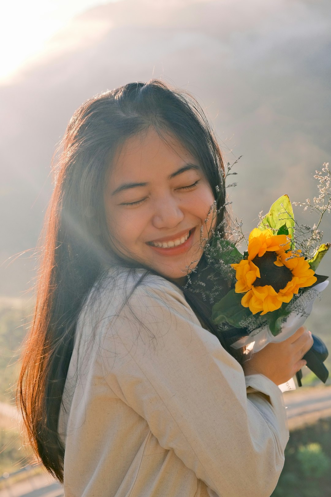 A woman smiles as she holds a bouquet of sunflowers