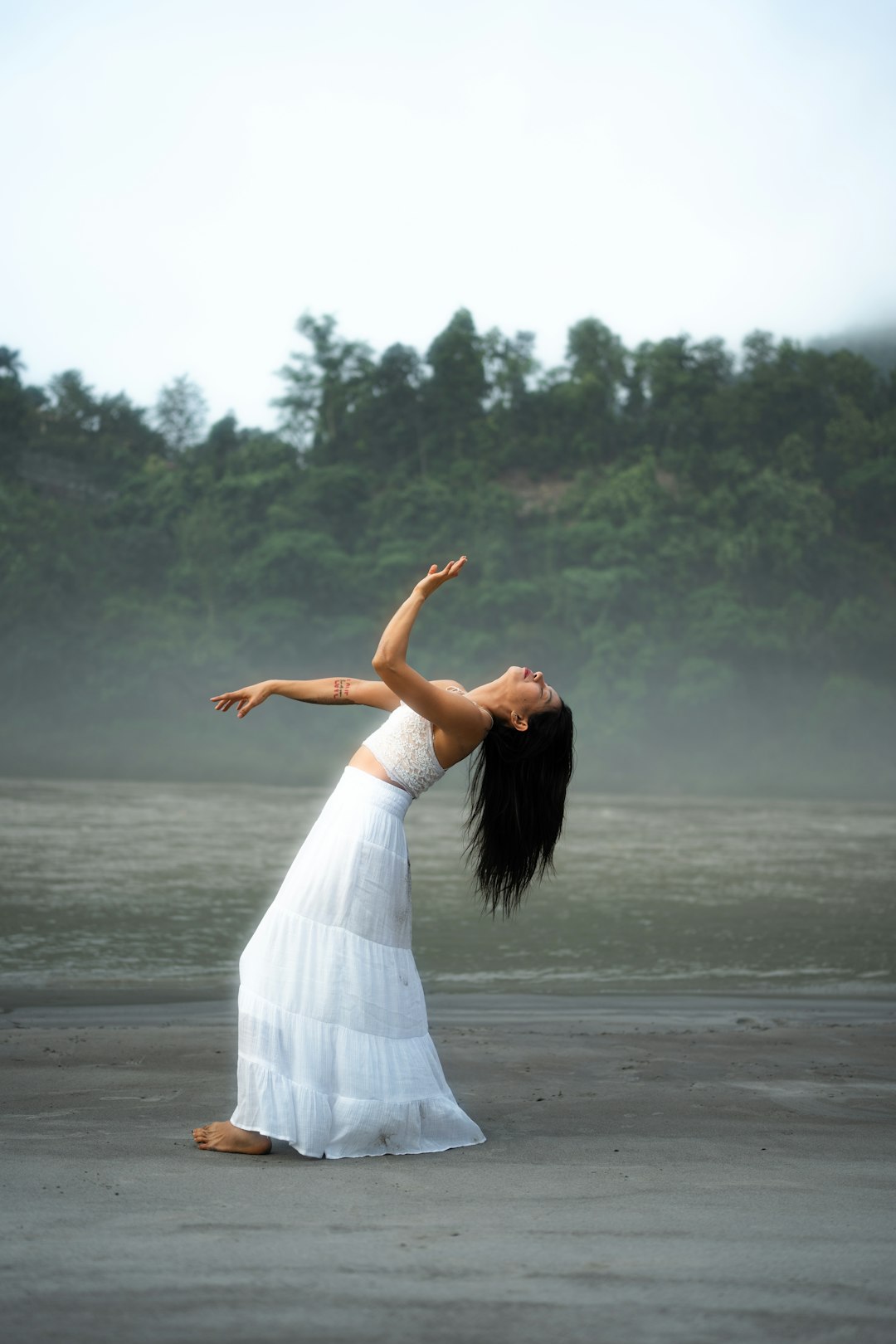 A woman in a white dress standing on a beach