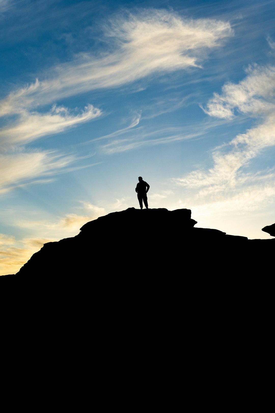 A person standing on top of a hill with a sky background