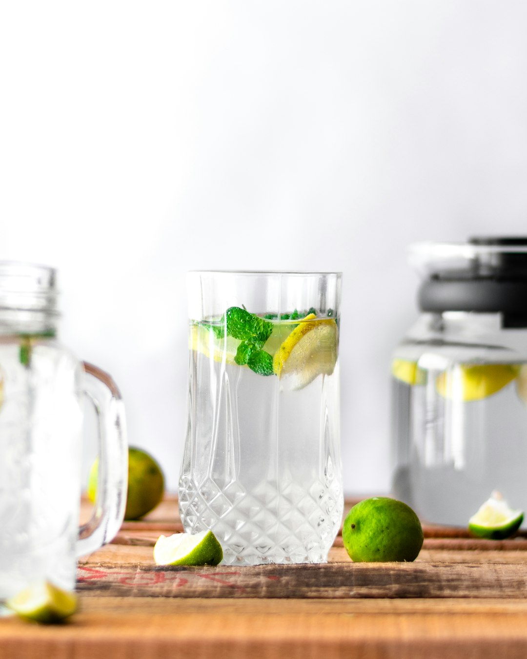 a glass of water with fruit and a lemon slice on a cutting board