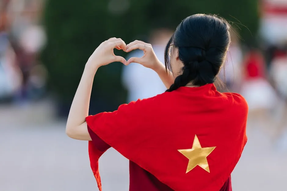 Woman wrapped in Vietnamese flag forming a heart shape with hands, symbolizing patriotism and love.